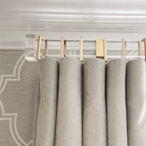 May include: A set of gray curtains with a decorative trim hanging from a clear acrylic curtain rod with gold accents.