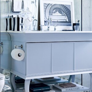 a bathroom vanity with a white countertop, a framed black and white photograph, and various toiletries and decor items.