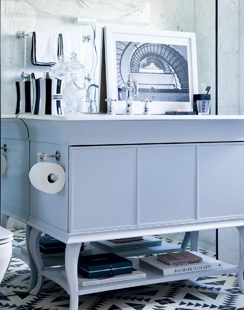 a bathroom vanity with a white countertop, a framed black and white photograph, and various toiletries and decor items.