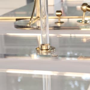 a close-up view of a clear glass surface with a brass-colored metal fixture, including a faucet and a decorative piece.