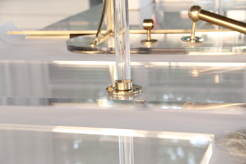 a close-up view of a clear glass surface with a brass-colored metal fixture, including a faucet and a decorative piece.