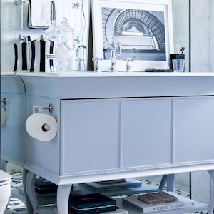 a bathroom vanity with a white countertop, a framed black and white photograph, and various toiletries and decor items.