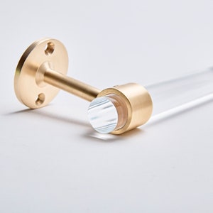 Detail shot of satin brass hardware ring fitted around a acrylic rod to be used as a wall mounted toilet paper holder.