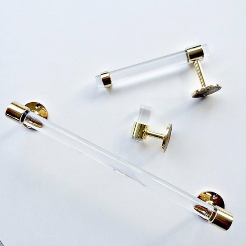 A set of bathroom accessories made of lucite and solid brass. The bath set includes a towel bar, robe or towel hook, and matching toilet paper holder.