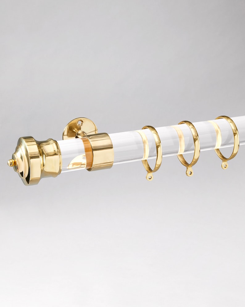 Round acrylic drapery rod with imperial style finial/end cap in polished brass gold finish.