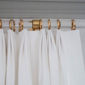 a white curtain with gold rings hanging from it