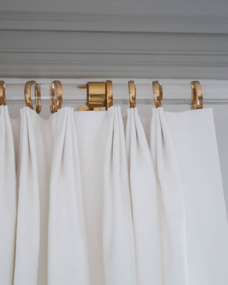 a white curtain with gold rings hanging from it