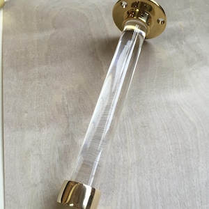 a clear glass tube with a gold-colored base, resting on a wooden surface.