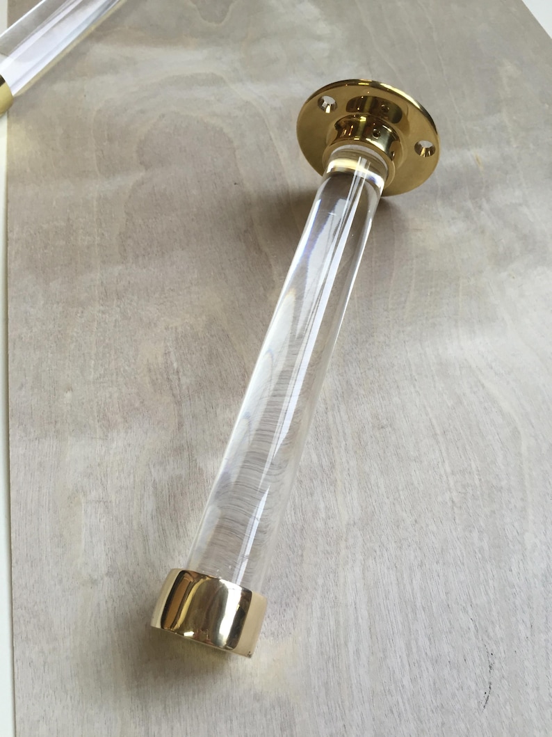 a clear glass tube with a gold-colored base, resting on a wooden surface.