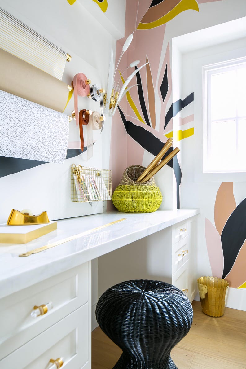 a white desk topped with a yellow vase next to a window