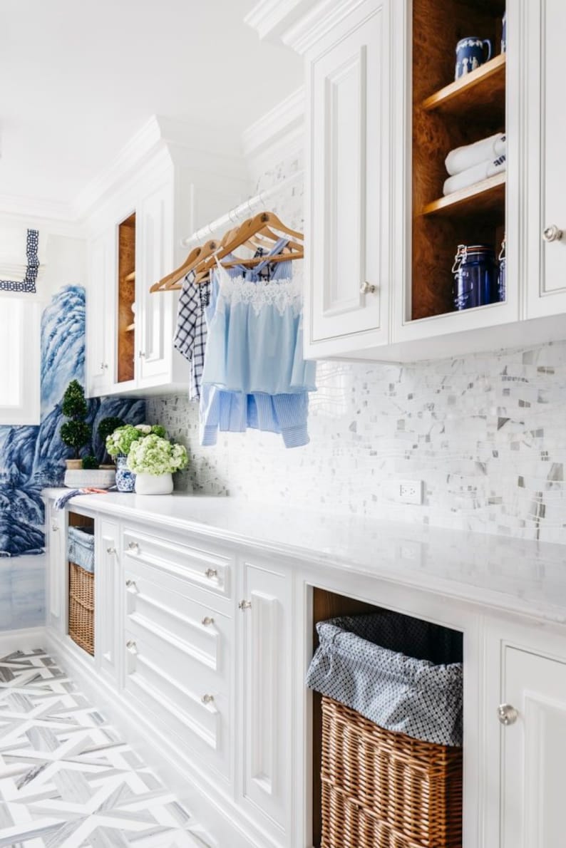 Large white laundry room featuring a clear acrylic rod, installed between two sets of upper cabinets, used to hang clean laundry to dry.
