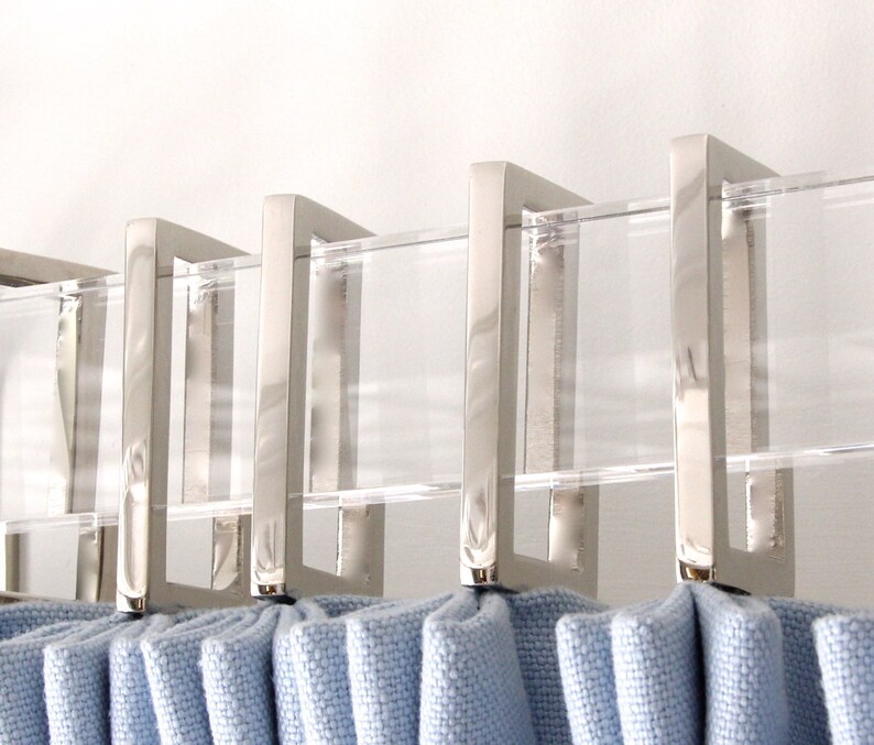 Row of silver rectangular curtain rings in shiny polished nickel finish.