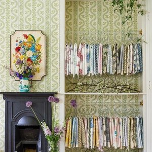 Clear lucite rods installed in a closet, featuring sage green patterned wallpaper, used to hang fabric samples.