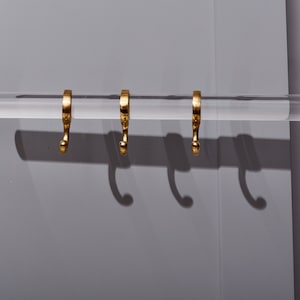 a pair of gold earrings hanging from a hook