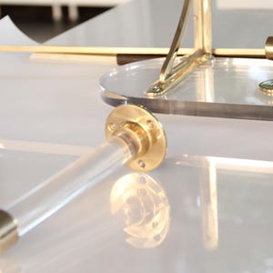 a close-up view of a transparent brass piece with a reflective surface, placed on a white surface.