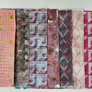 May include: A collection of seven handmade paper samples with different patterns and colors. The patterns include pink with yellow dots, green and gray geometric shapes, blue and pink geometric shapes, a pink and blue diamond pattern, a white and pink diamond pattern, and a pink and green geometric pattern.