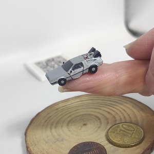 Könnte beinhalten: Eine weiße Keramik-Tasse mit schwarzem Henkel und dem Text "But First, Coffee" in schwarzer, handschriftlicher Schrift. Die Tasse steht auf einer weißen Oberfläche.