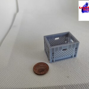 May include: A miniature gray plastic crate, approximately the size of a US penny, for use in dollhouses or model railroad layouts.