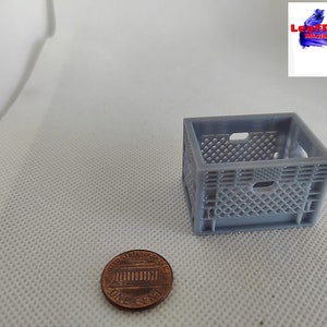 May include: A gray plastic crate, approximately 2 inches tall, next to a US penny. The crate has a grid pattern and is made for holding small items.