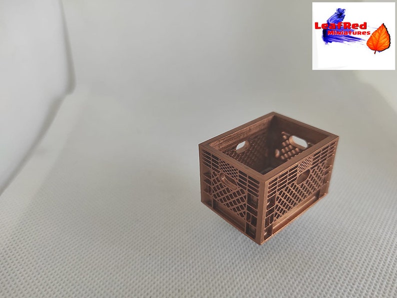 May include: A miniature brown plastic crate, similar to a milk crate, with a grid pattern. The crate is empty and appears to be made of a sturdy material.