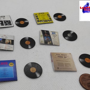 Pu&ograve; includere: Una collezione di dischi in vinile in miniatura e copertine di album con Elvis Presley. I dischi sono neri con un'etichetta dorata. Le copertine degli album sono di vari colori e presentano immagini di Elvis Presley.