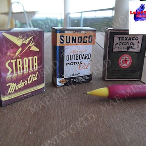 May include: Three miniature vintage oil cans. The cans are red, green, and yellow with white lettering. The cans are labelled "Strata Motor Oil", "Sunoco Special Outboard Motor Oil", and "Texaco Motor Oil F For Four Cars".