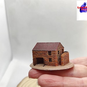 Puede incluir: Edificio de ladrillo en miniatura con tejado de tejas rojas, dos ventanas y una puerta abierta. El edificio está sobre una base circular. El logotipo de LeafRed Miniatures está en la esquina superior derecha.