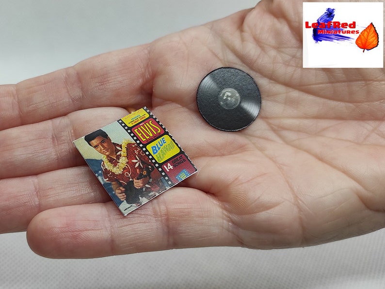 Pu&ograve; includere: Un disco in vinile in miniatura e una copertina di album in miniatura con Elvis Presley. La copertina dell'album &egrave; rossa, gialla e blu con il titolo "Elvis Blue Hawaii" e il testo "14 Great Songs".