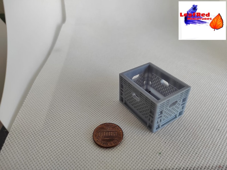May include: A small gray plastic crate, about the size of a US penny, for miniature crafts and model making.