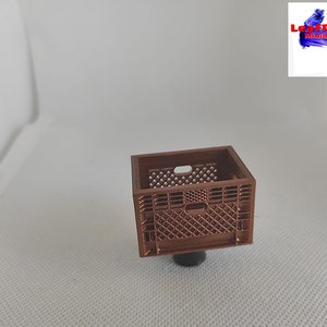 May include: A miniature brown plastic crate with a grid pattern. The crate is about 1 inch tall and 1 inch wide.