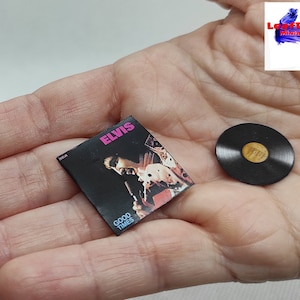 Pu&ograve; includere: Un disco in vinile in miniatura e una copertina di album con Elvis Presley. La copertina dell'album &egrave; nera con un design rosa e bianco e il testo "Elvis" e "Good Times". Il disco &egrave; nero con un'etichetta dorata.