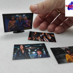 Op de afbeelding: Een miniatuurtelevisie met een zwart frame en een scherm waarop een groep mensen te zien is. Er zijn vier kleinere foto's van dezelfde groep mensen in verschillende poses.