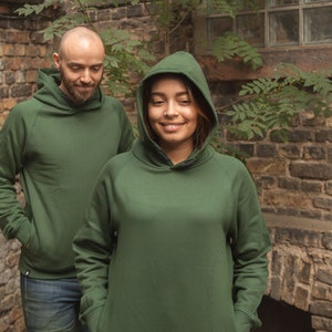 Könnte beinhalten: Zwei Personen tragen grüne Kapuzenpullover. Die Person links trägt einen dunkelgrünen Kapuzenpullover mit einem Kordelzug. Die Person rechts trägt einen hellgrünen Kapuzenpullover mit einem Kordelzug.