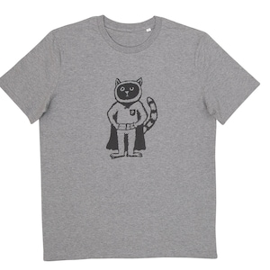 Può includere: T-shirt grigio con un disegno di un gatto supereroe dei cartoni animati. Il gatto indossa un mantello e una cintura neri e ha una coda a strisce. L'illustrazione è stampata con inchiostro nero sulla parte anteriore della maglietta.