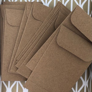 Op de afbeelding: Een stapel bruine kraftpapier enveloppen. De enveloppen zijn gevouwen en klaar om te worden gebruikt voor verzending.