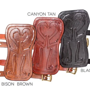 Puede incluir: Tres protectores de brazo de cuero con tallas decorativas. Los protectores de brazo son de color marr&oacute;n bisonte, marr&oacute;n ca&ntilde;&oacute;n y negro. Cada protector de brazo tiene una hebilla y una correa.