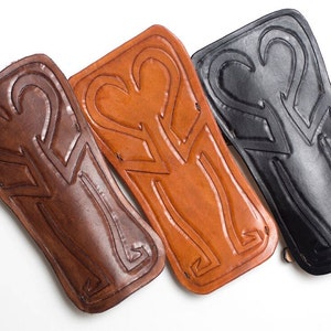 Puede incluir: Tres protectores de brazo de cuero con un dise&ntilde;o decorativo en relieve. Los protectores de brazo son marrones, tostados y negros.