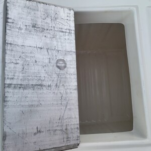 May include: A white rectangular compartment with a metal door that is open. The door has a silver finish and is scratched.
