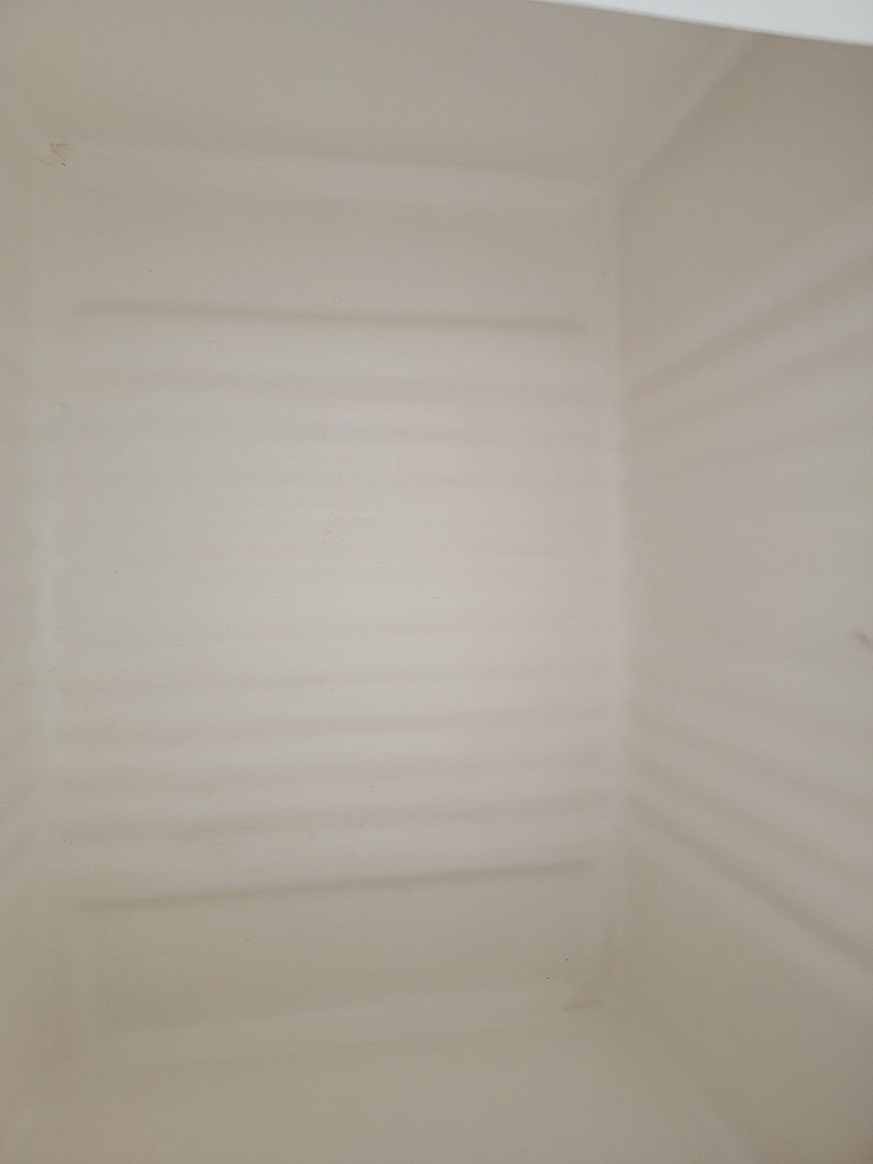 May include: The inside of a white plastic storage container with a smooth, textured surface.
