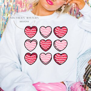 May include: White sweatshirt with the text "Southern Winters Designs" and a pattern of nine pink and red hearts with white sprinkles.