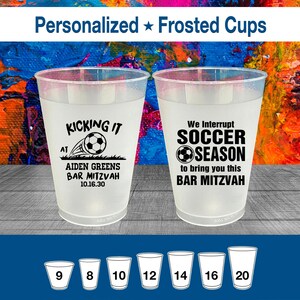 May include: Two clear, frosted plastic cups with black text. One cup says "KICKING IT AT AIDEN GREENS BAR MITZVAH 10.16.30" with a soccer ball graphic. The other says "We Interrupt SOCCER SEASON to bring you this BAR MITZVAH".