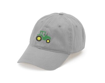 Puede incluir: Una gorra de béisbol gris claro con un tractor verde bordado con ruedas amarillas en el panel frontal. La gorra tiene una visera curva, un botón en la parte superior y ojales cosidos para la ventilación, ofreciendo un ajuste estructurado.