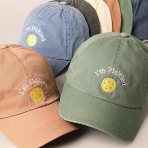 May include: Three different colored baseball caps with the phrase "I'm Pickled" and a yellow pickleball embroidered on the front.