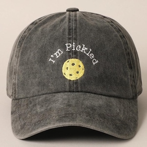 K&ouml;nnte beinhalten: Eine schwarze, abgenutzte Baseballkappe mit dem gestickten Text "I'm Pickled" in Wei&szlig; und einem gestickten gelben Pickleball in der Mitte.