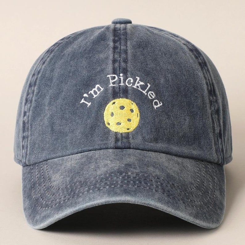 K&ouml;nnte beinhalten: Eine dunkelblaue Baseballkappe aus Denim mit dem in Wei&szlig; gestickten Text "I'm Pickled" und einem in der Mitte gestickten gelben Pickleball.