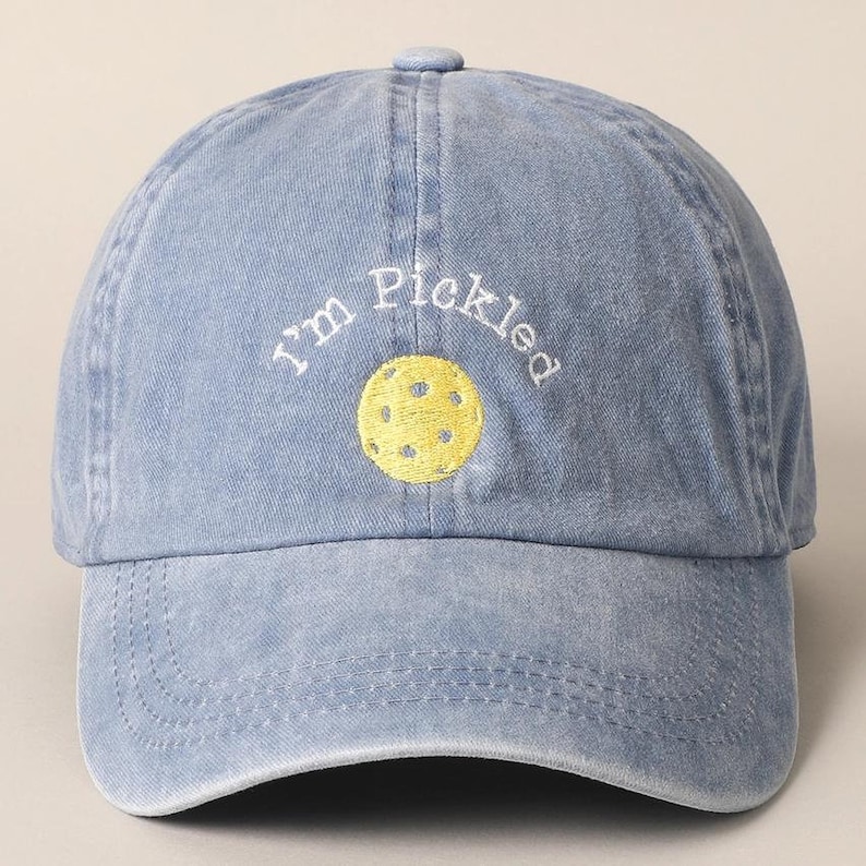 K&ouml;nnte beinhalten: Eine blaue Baseballkappe aus Denim mit wei&szlig;er Stickerei, auf der "I'm Pickled" steht, und einem gelben gestickten Pickleball.