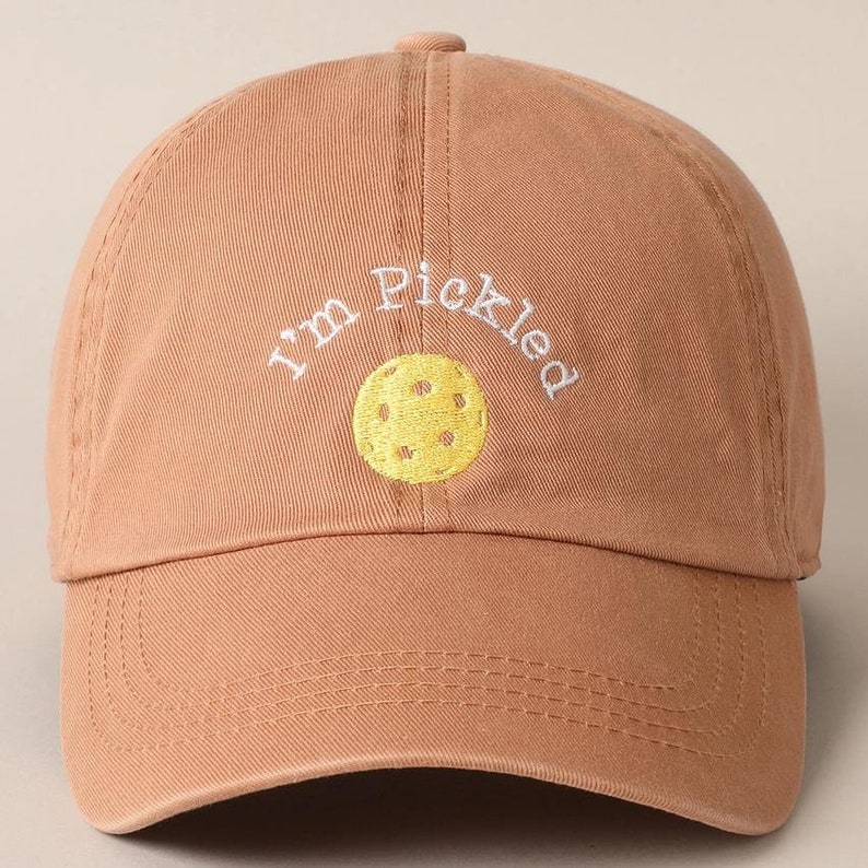 K&ouml;nnte beinhalten: Eine braune Baseballkappe mit dem Text "I'm Pickled" in wei&szlig; gestickt und einem gelben Pickleball-Motiv.
