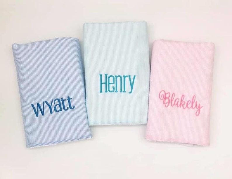 May include: Three personalized baby blankets, one light blue with the name Wyatt, one light blue with the name Henry, and one pink with the name Blakely.