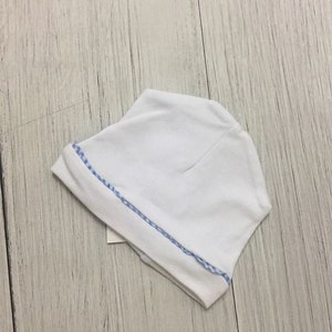 May include: White baby hat with a blue and white trim.