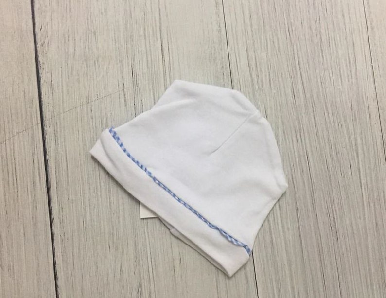 May include: White baby hat with a blue and white trim.